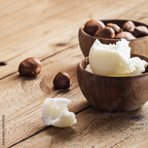 Shea butter and nuts on a wooden board, copy space.