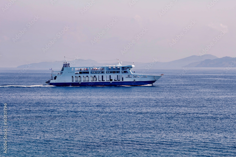 Ferryboat with cars and people cruising on water at sunset. Greece, Corfu