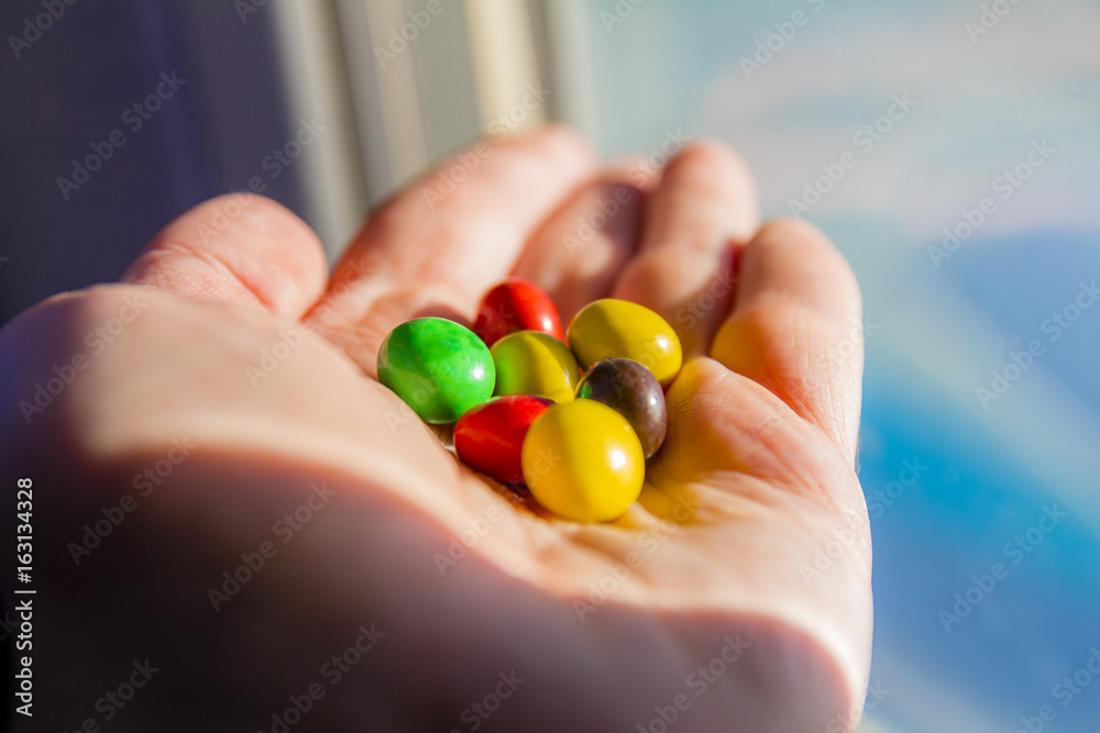 Man hand holding colorful chocolate candies buttons Man hand holding colorful chocolate candies buttons