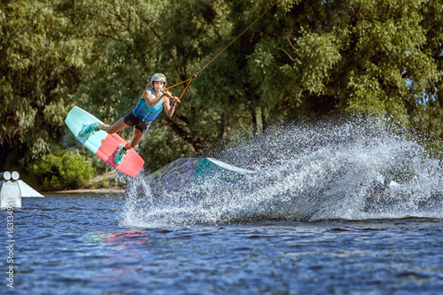 Professional sportswoman in training on wakeboarding. She jumps on the water on the board.
