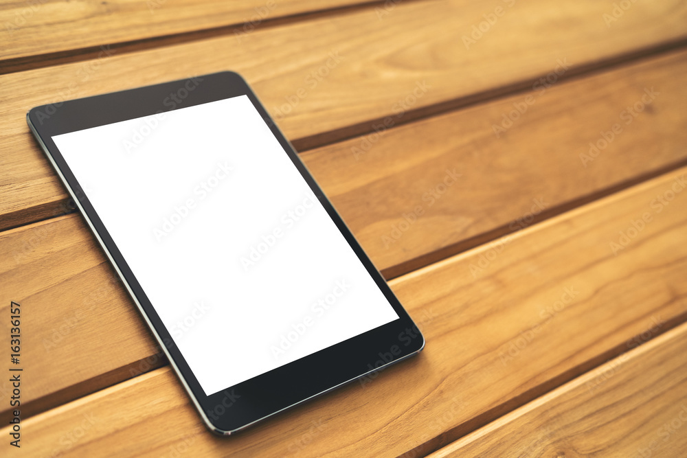 Mockup image of black tablet pc with blank white screen on vintage wooden table background Mockup image of black tablet pc with blank white screen on vintage wooden table background