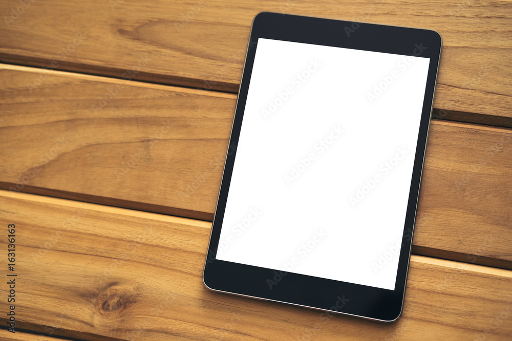 Mockup image of black tablet pc with blank white screen on vintage wooden table background Mockup image of black tablet pc with blank white screen on vintage wooden table background