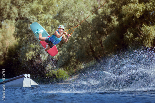 Professional athlete during a wakeboard trick on the water.