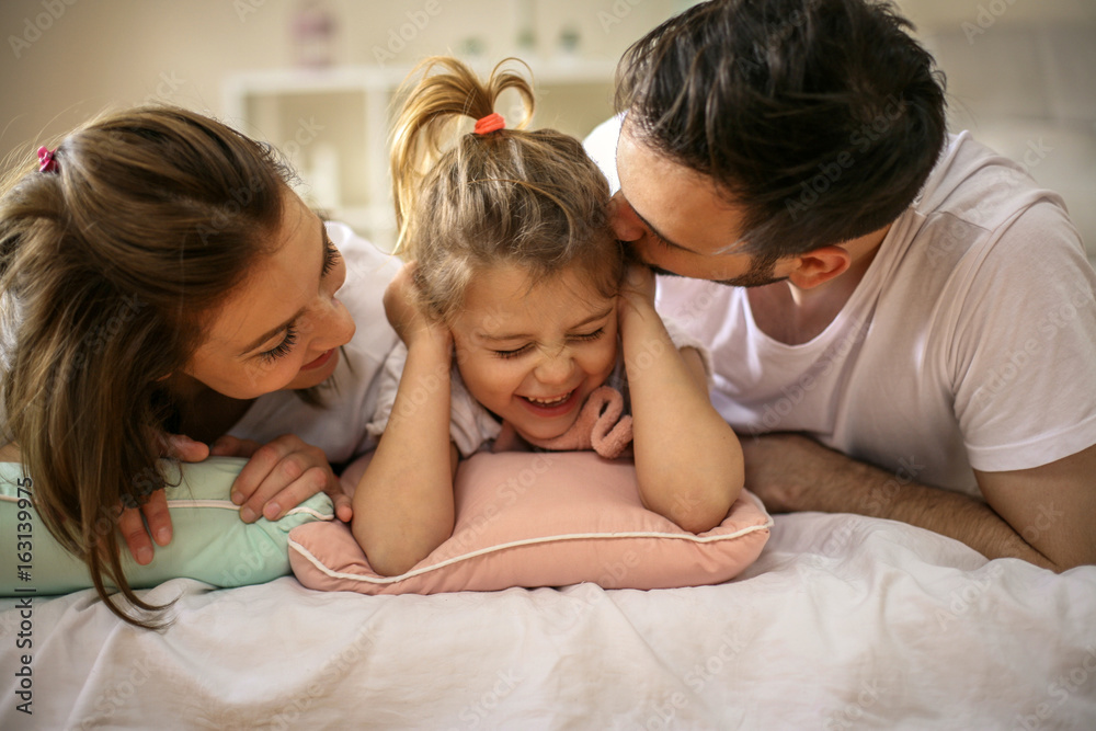 Family with one daughter lying on bed.