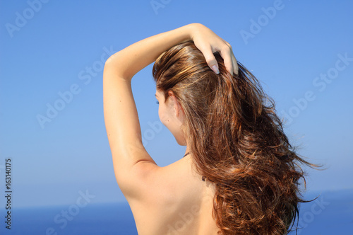 Young Beautiful Woman Sunbathing on the Beach on Background of Warm Blue Sea and Deep Blue Sky. Summer Vacation.