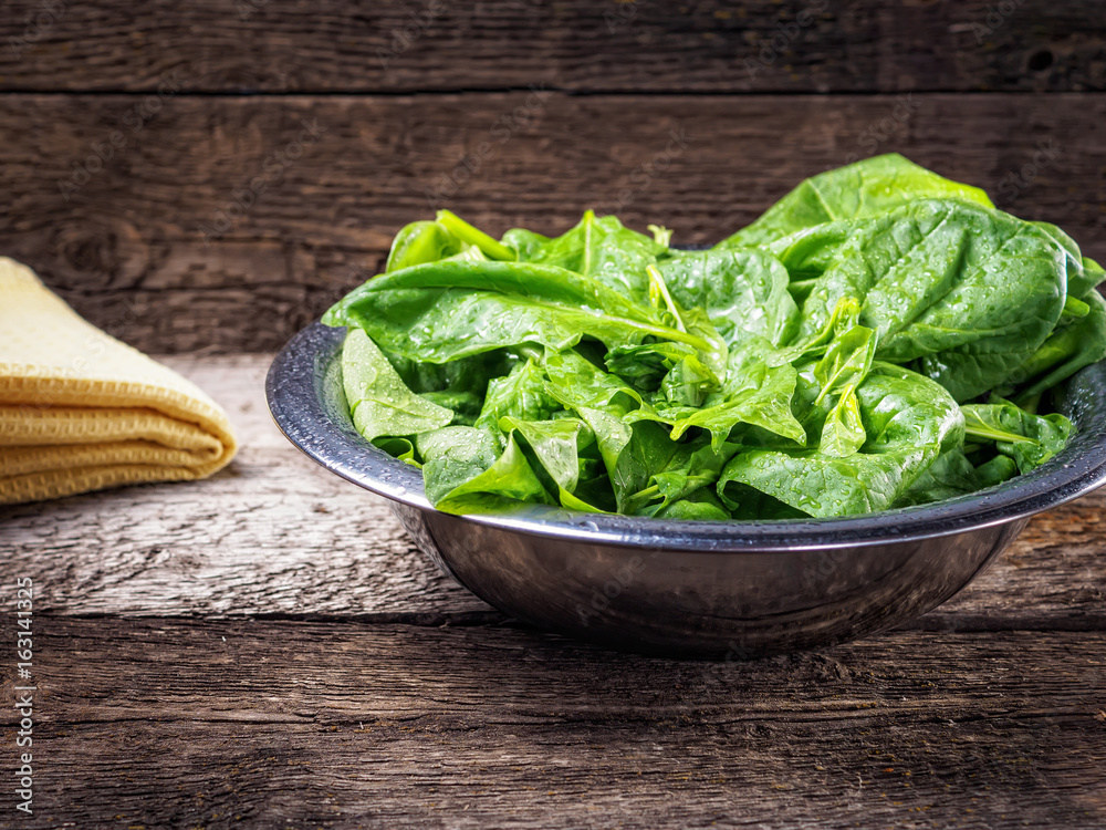 Spinach leaves in bowl on wooden background Spinach leaves in bowl on wooden background