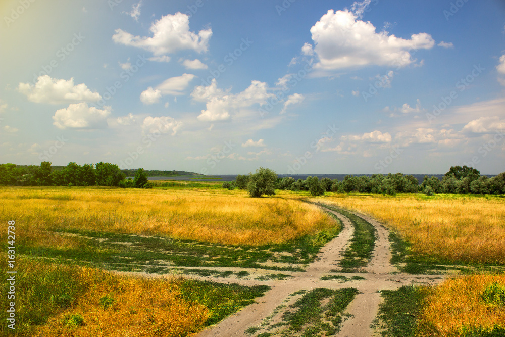 Obraz premium Crossroad of a rural road, on a hot summer day