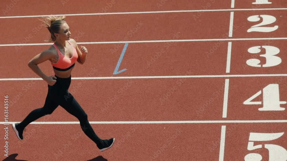 Young adult sport woman sprinter athlete running on stadium track in slow motion Young adult sport woman sprinter athlete running on stadium track in slow motion