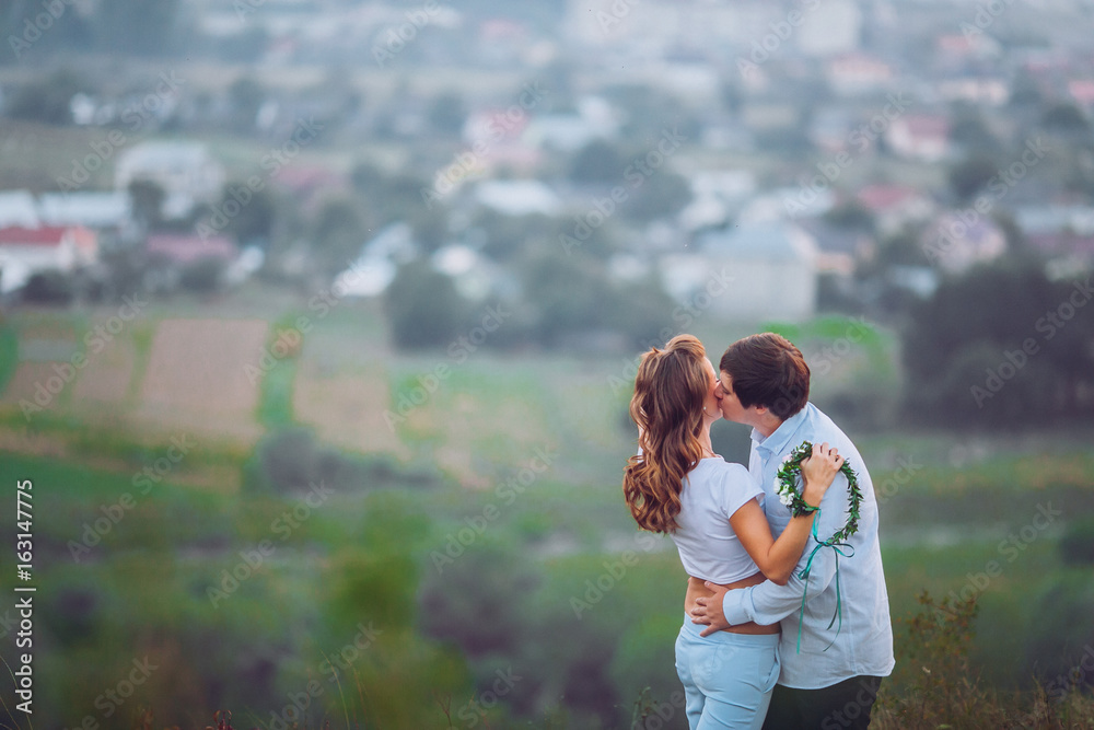 Fototapeta premium Romantic couple at sunset on bright yellow sky and city background, love tenderness concept, young adult people