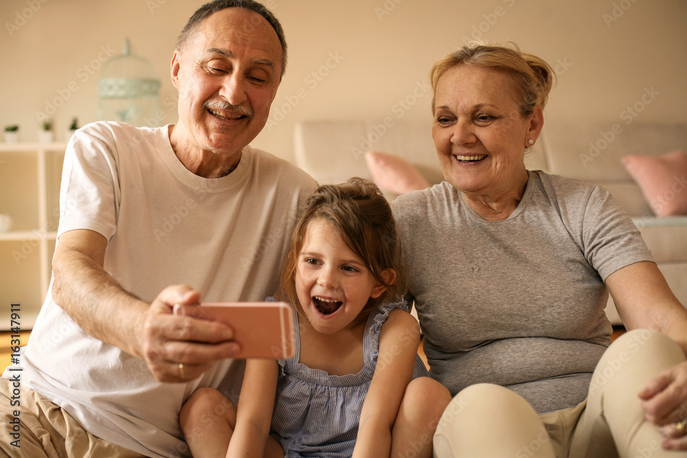 Grandmother and grandfather with their granddaughter using smart phone. Grandmother and grandfather with their granddaughter using smart phone.