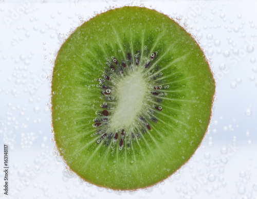Slice of kiwi in water with air bubbles on it