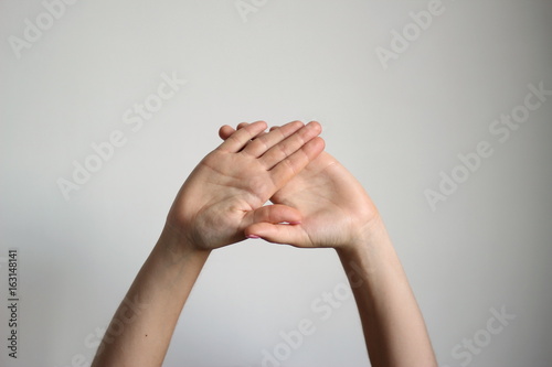 Young woman's fold one's palm isolated on light gray background. Gesture