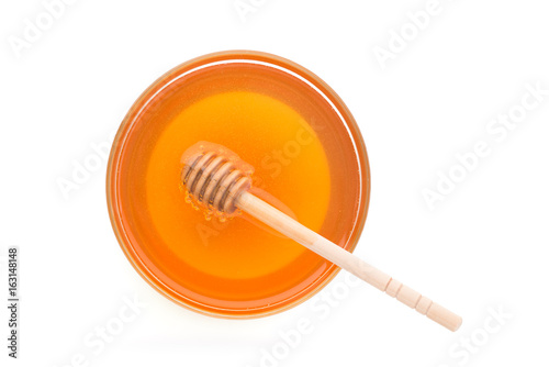 Wooden dipper with bowl of honey, isolated on the white background