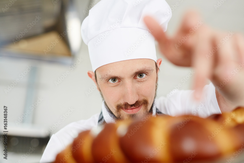 Young baker looking at freshly baked bread Young baker looking at freshly baked bread