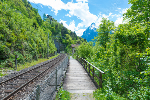 Railway track. A path and a bridge along the railway. Alps Switzerland.