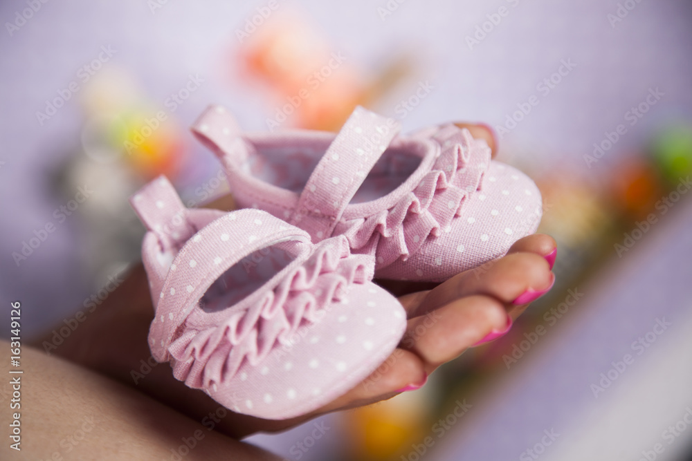 Pregnant woman holding baby shoes in her hands Pregnant woman holding baby shoes in her hands