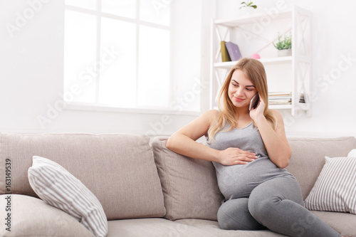 Smiling pregnant woman talking on her smartphone