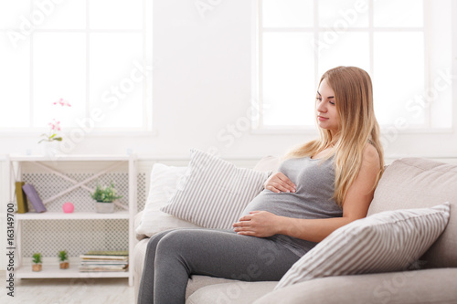 Pegnant woman caressing her belly at home