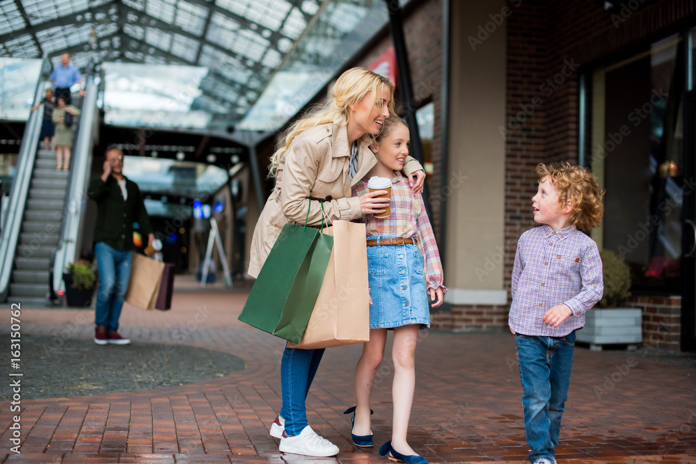 young mother talking with her little kids during shopping at shopping centre