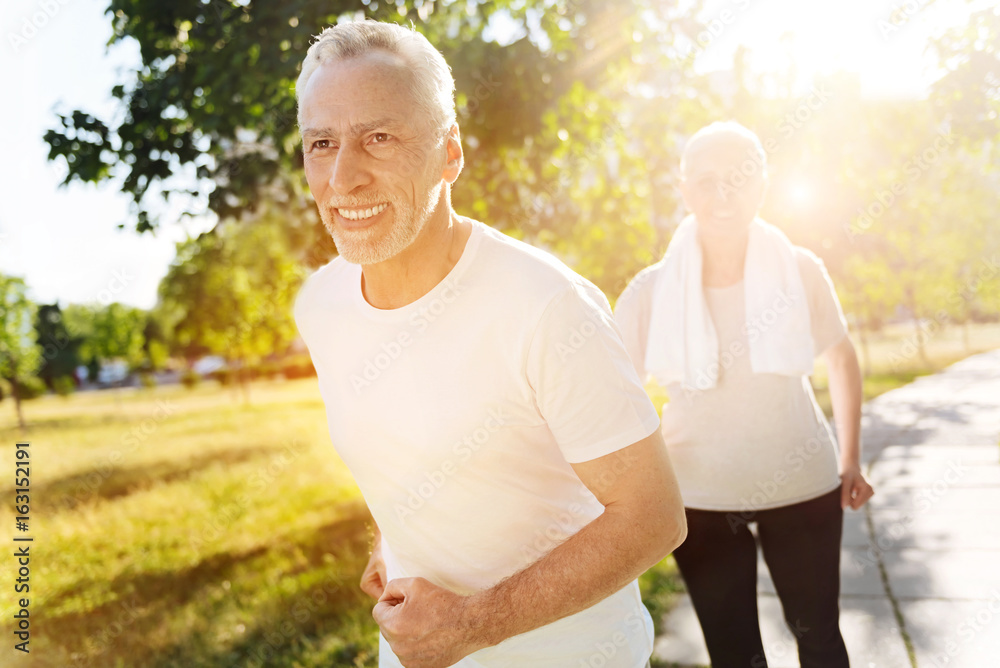 Cheerful retired man jogging with his wife