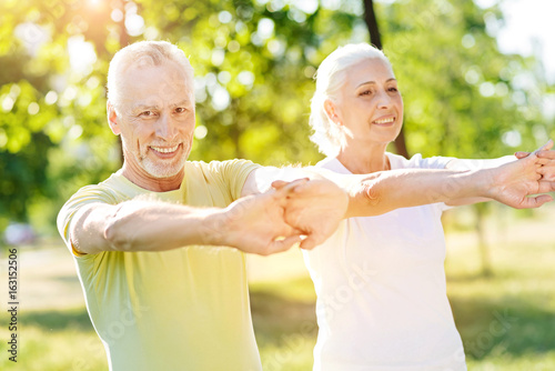 Joyful aged couple enjoying sport exercises