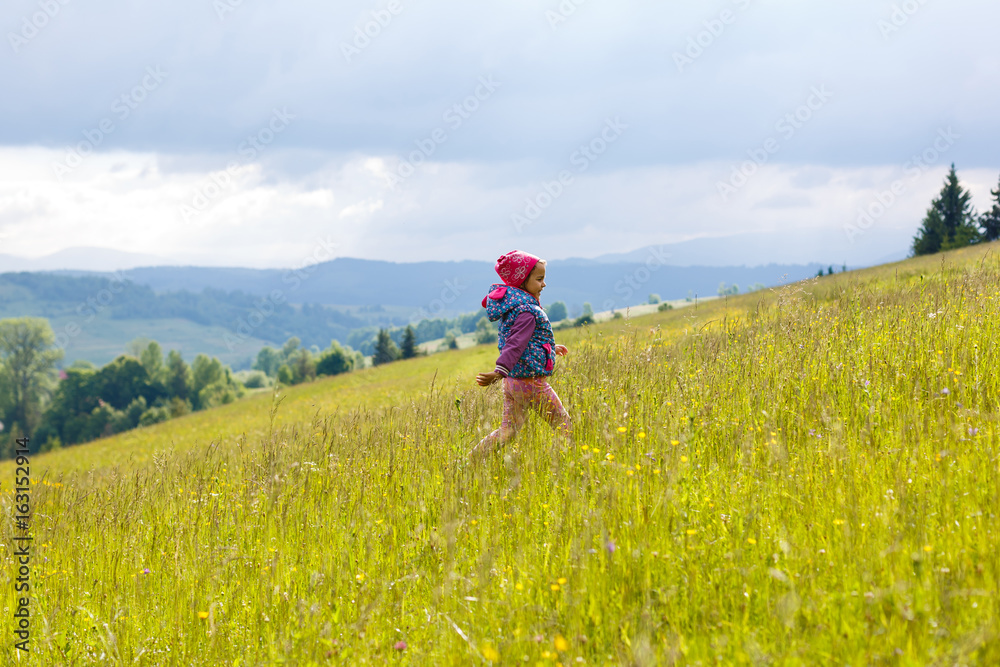 A little girl is running around the mountains