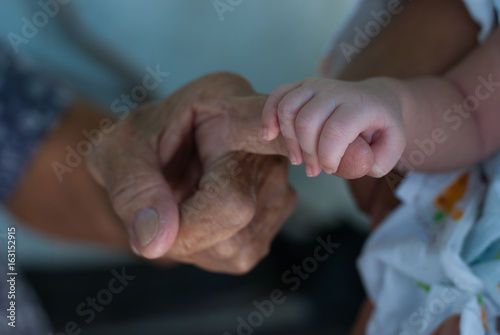 old people and baby holding hands 