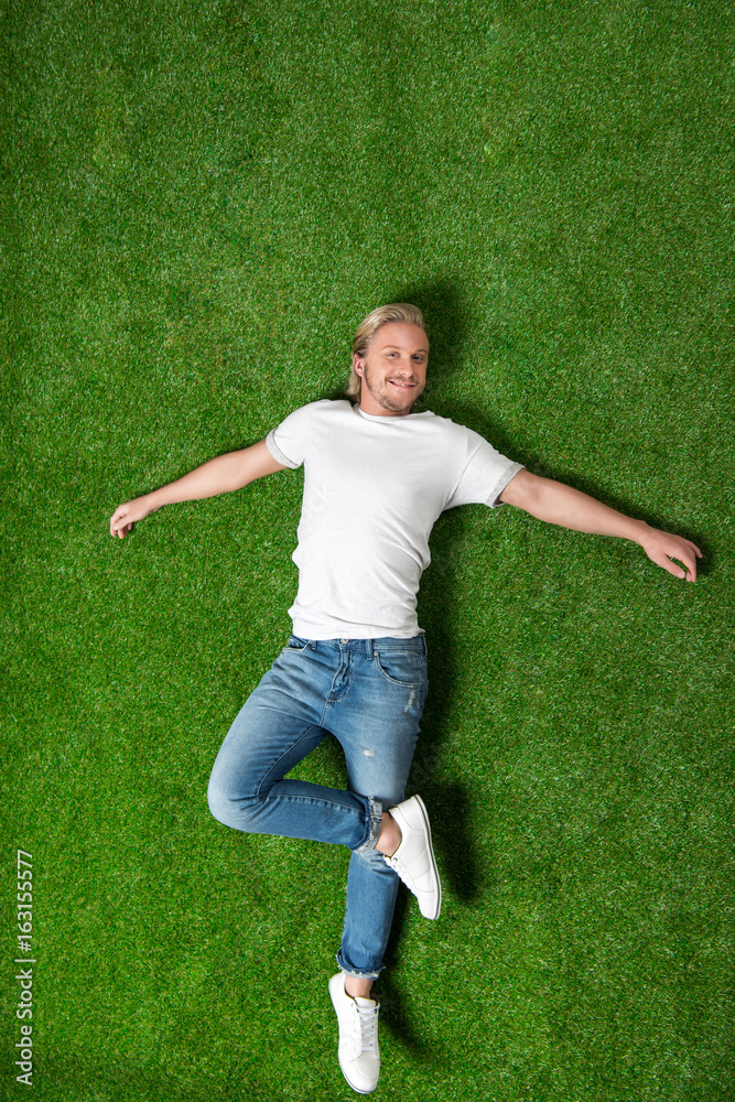 above view of young caucasian man relaxing and lying on meadow above view of young caucasian man relaxing and lying on meadow