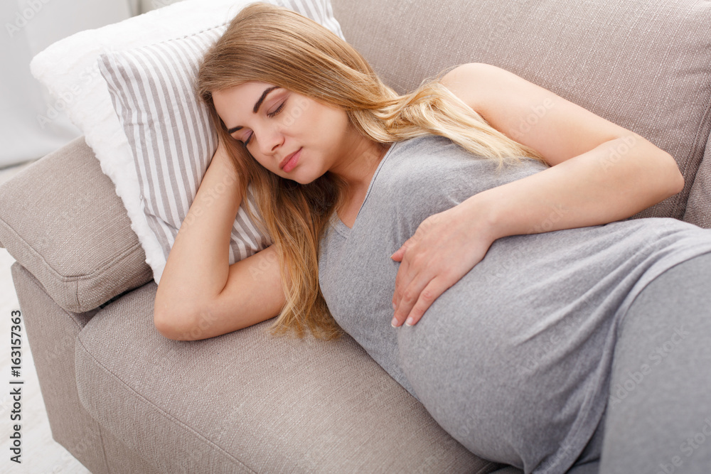 Beautiful pregnant woman napping on sofa