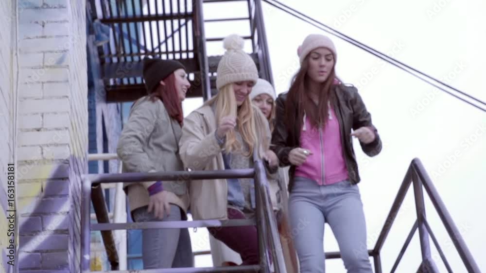 Group Of Teens Dance To A Song On A Smartphone On A Fire Escape In A City Group Of Teens Dance To A Song On A Smartphone On A Fire Escape In A City