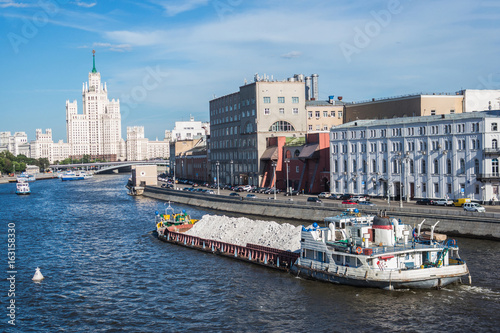 Barge with sand on Moskva river with skyscraper building view, Moscow