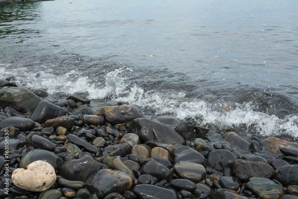 Black stones beach as a background, black stones coast with silky waves from long exposure at Lipe island in Thailand. Black stones beach as a background, black stones coast with silky waves from long exposure at Lipe island in Thailand.
