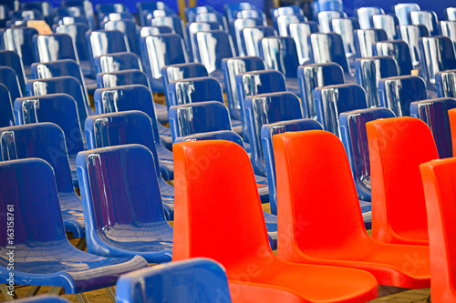 Straight lines of red and blue coloured empty plastic seats in a meeting area before the event