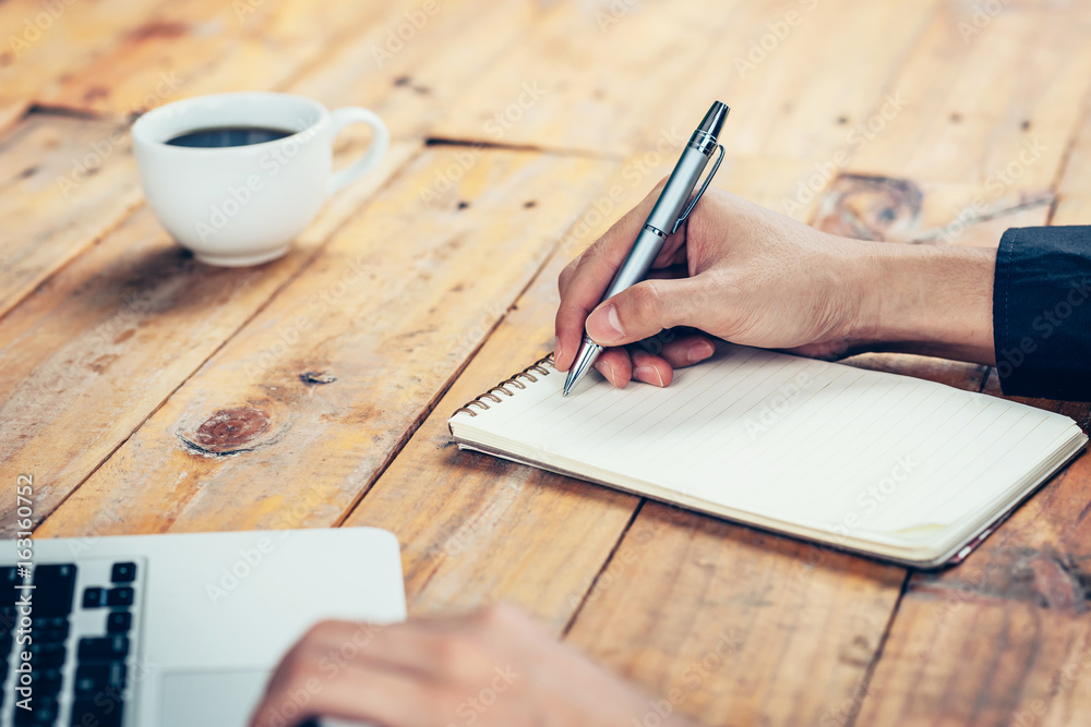 Hand business man writing notebook on wood table in coffee shop. Hand business man writing notebook on wood table in coffee shop.