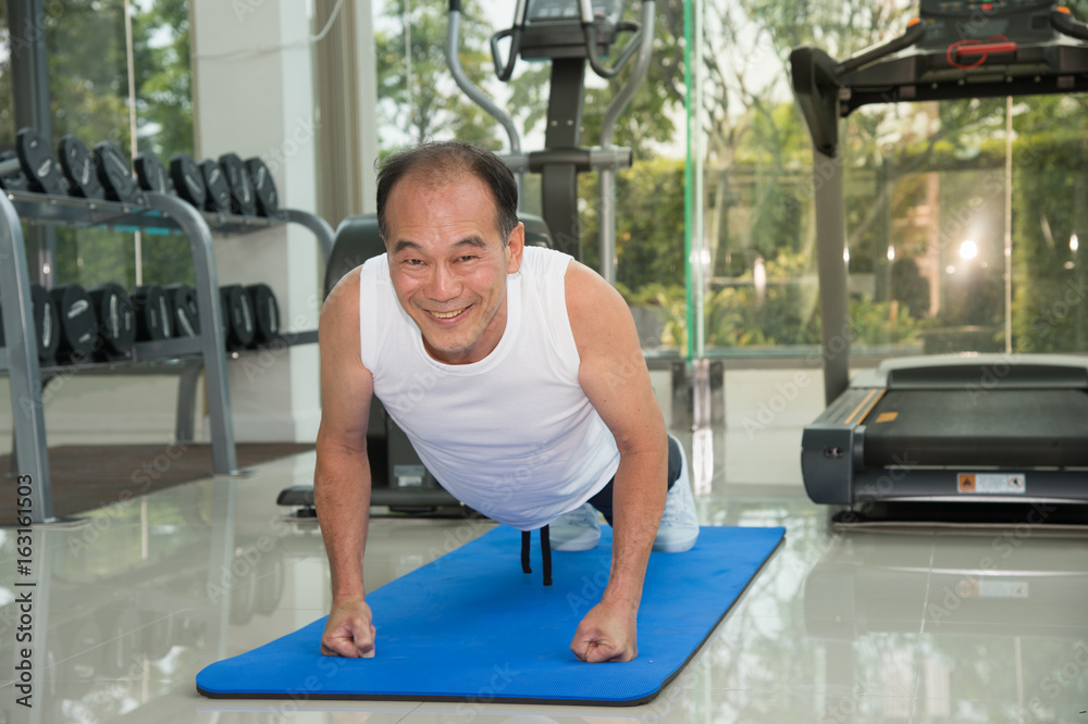 senior man fitness exercising by doing push ups in the fitness center or gym, sport and health concept.