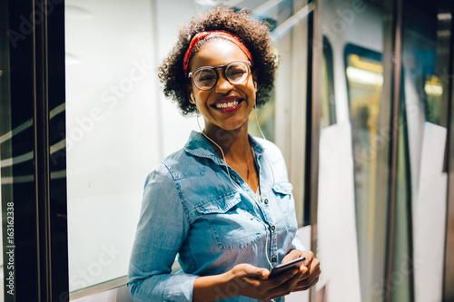 Smiling young African woman listening to music on a train photo