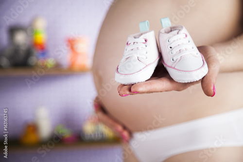 Pregnancy concept, female hands shoes 