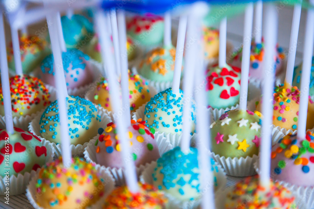 Colorful baked cakepops on white wooden background