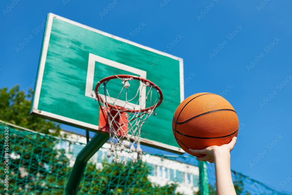 Hand with basketball on background of shield basket hoop