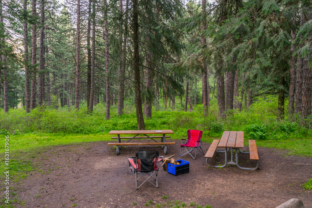 Table and red chairs on a background of the green forest.  Kamiak Butte State Park Campground,  Whitman County, Washington, USA  