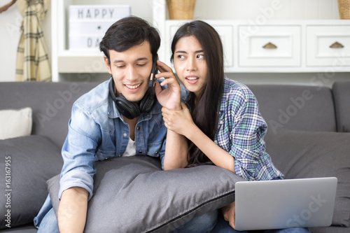 Young man using smartphone and woman try to listen at living room, people lifestyle concept.