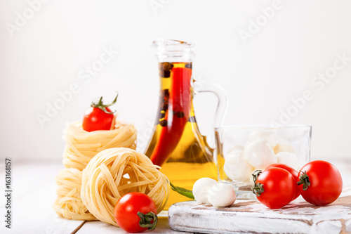 Olive oil with pepper in a bottle, paste, cheese and tomatoes on a light background. Selective focus. Copy space