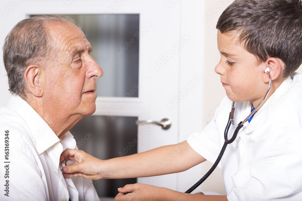Fototapeta premium Kid examines his grandfather using stethoscope
