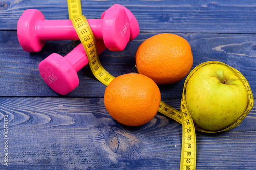 diet concept, dumbbells weight with measuring tape, orange and apple