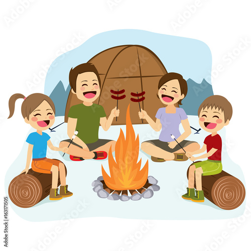 Happy family cooking sausages and marshmallows on campfire