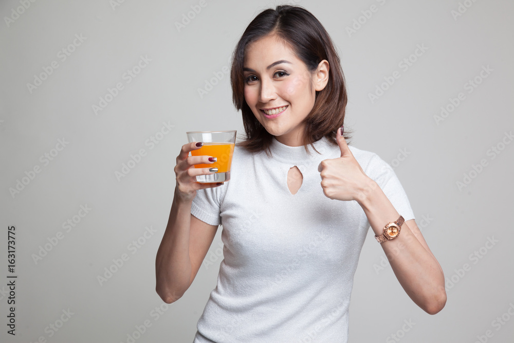 Young Asian woman thumbs up drink orange juice. Young Asian woman thumbs up drink orange juice.