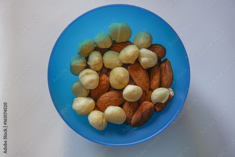 Macadamia and almonds mixed roasted nuts top closeup view.
Collection of healthy nuts served on a blue plastic bowl. Macadamia and almonds mixed roasted nuts top closeup view.
Collection of healthy nuts served on a blue plastic bowl.