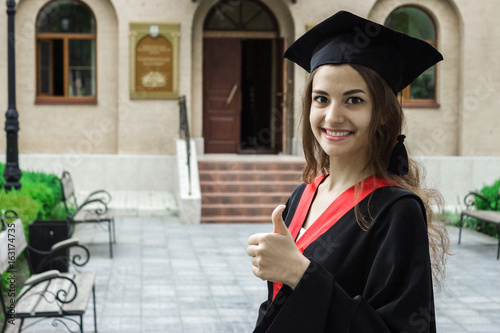 Woman portrait on her graduation day. thumbs up. University. Education, graduation and people concept.
