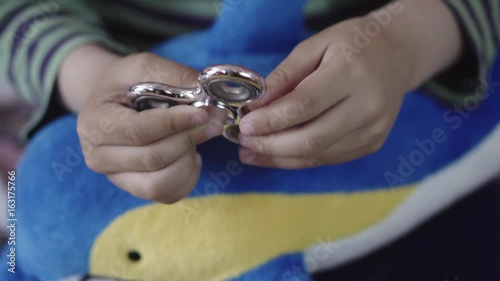 Hand spinner or fidgeting spinner rotating on child's hand (Only the hands) photo