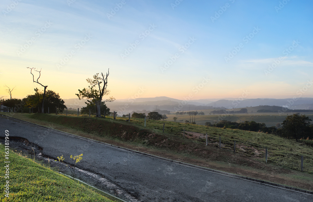 Sunrise in a road by the mountains with a scenic view of the countryside Sunrise in a road by the mountains with a scenic view of the countryside